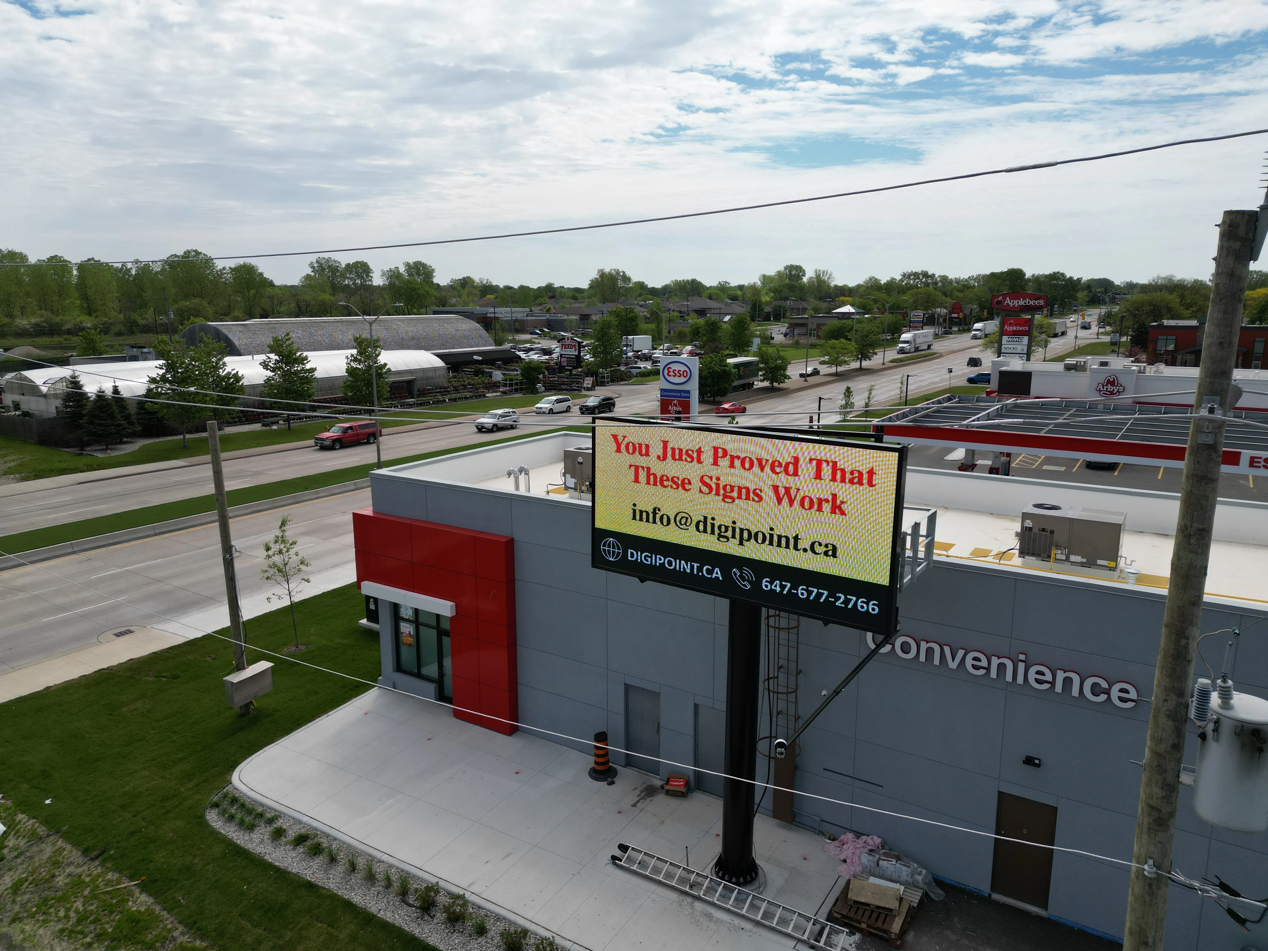 A digital billboard near Highway with cars and truck going around it and seeing the billboard advertisment.